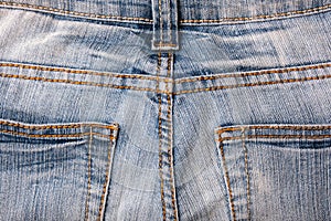 Back pockets of blue shabby grange jeans close up
