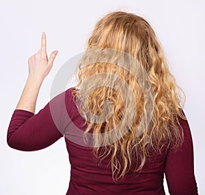 Back portrait of redhead curly woman shows something