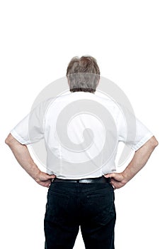 Back pose of a senior man standing with hands on his waist