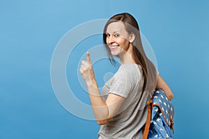 Back rear view of young attractive brunette woman student with backpack looking back pointing index finger on camera