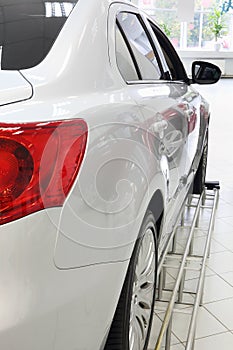Back red lights of new white shining car standing in office