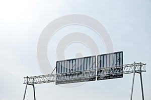 The back of a road or expressway sign showing the sign's steel structure over clear sky and sunlight.