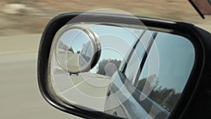 Back road reflected in car mirror, car driving fast on a motorway