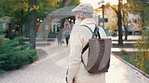 Back of an senior man walking at city