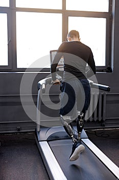 back shot of man with artificial legs running on treadmills at gym