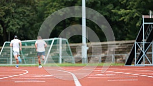 Back shot of two Caucasian young men ready for running on the track