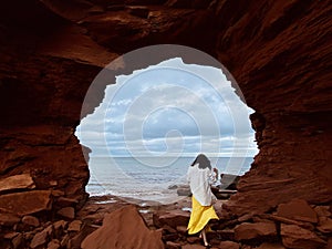 Back shot of a woman walking on rocks under the sea cliffs at Cavendish Beach, Prince Edward Island