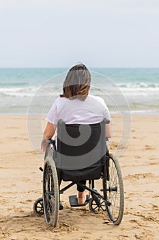 Back shot of a woman in a wheelchair at the beach