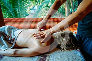 Back and shoulder massage close-up. Pain relief with massage. Young girl lies on special table during session of wellness massage