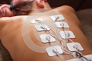 Muscle stimulator with electrodes, bacBack and shoulder massage with a muscle stimulator with attached electrodes along the spine