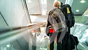 Back side of couple backpacker using escalator in airport for travel and copy space