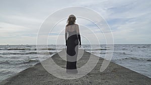 Back side of elegant woman walking on the pier at the beach. Summer vacation holiday concept