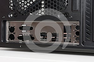 Back side of empty midi tower computer case on white table.