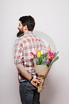 Back side of Handsome young man with beard and nice bouquet of flowers