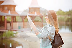 Back side of traveler girl searching right direction on map, orange sunset light, traveling along Europe