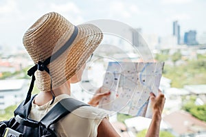 Back side of traveler girl searching right direction on map, traveling along Asia