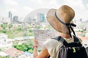 Back side of traveler girl searching right direction on map, traveling along Asia