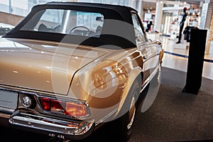 Back and side view of beige retro cabriolet car with close up of right chrome backlight, bumper, disk and wheel arch