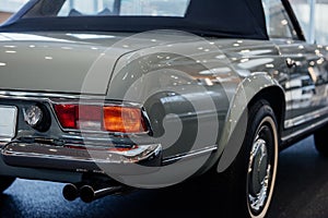Back and side view of grey retro cabriolet car with close up of right chrome backlight and exhaust pipe, wheel arch