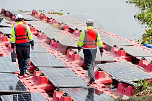 Back and side view of professional with safety uniform walk on footpath along row of solar cell panels in workplace concept of