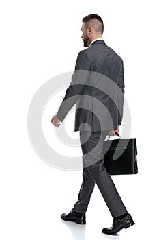 Back side view of a walking businessman holding a briefcase