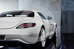 Back, side view of white cool sport car with right diode backlight, blue mirror with turn signal, trunk, light alloy