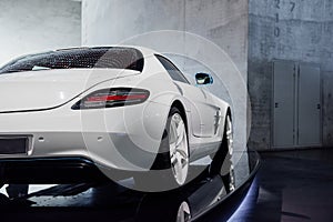 Back, side view of white fast sport car with right diode backlight, blue mirror with turn signal, trunk, light alloy