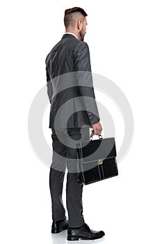 Back side view of a young businessman holding  suitcase