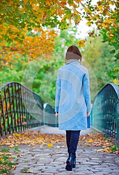 Back side view at Young redhead woman in blue coat