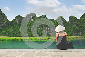 Back side of woman sitting in front of mountain in Ninh Binh