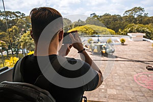 Back side of Young Asian traveling men taking a photo of Independence Palace in Ho Chi Minh City, Vietnam