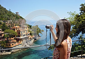 Back side of young woman taking picture of beautiful italian bay in Portofino, happy travel to Europe, summer vacation concept