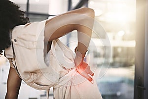 The back is susceptible to stress. a young businesswoman experiencing back pain while working in a modern office.