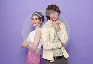 Back-to-back photo of young happy smiling cheerful couple of friends with crossed hands isolated on purple background