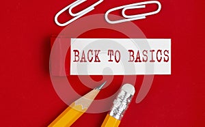 BACK TO BASICS message written on torn red paper with pencils and clips, business concept
