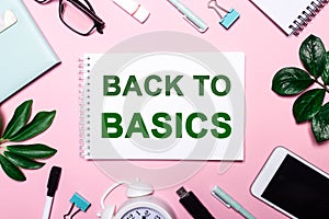 BACK TO BASICS written on a pink background surrounded by stationery and plant leaves. Business concept