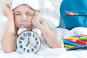 Back to school. Alarm,clock.Displeased girl,schoolgirl sleeps in bed,doesn`t want to wake up early to study.Backpack,colored
