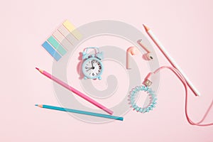 Back to school - alarm clock and pencils, headphones and stationery on pink background, girly set