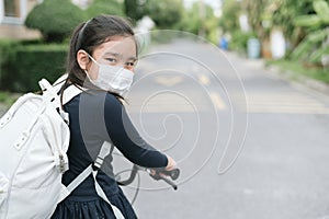 Back to school. asian child girl wearing face mask with backpack biking a bicycle and going to school .Covid-19 coronavirus