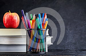 Back to school background with books and apple over blackboard with copy space
