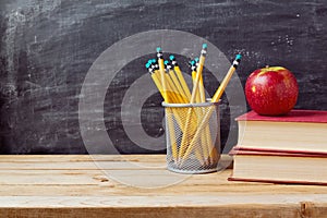 Back to school background with books, pencils and apple over chalkboard