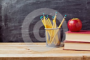 Torna a scuola di sfondo con libri, matite e apple lavagna e tavolo in legno.