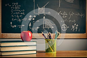 Back to school background with books, pencils and apple over chalkboard and wooden table