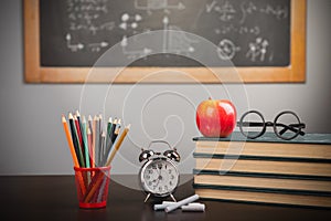 Back to school background with books, pencils and apple over chalkboard and wooden table