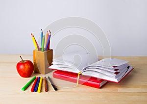 Back to school background with books, pencils and apple over wooden table