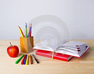 Back to school background with books, pencils and apple over wooden table