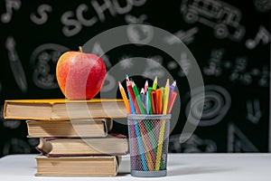 Back to school background with books, pencils and apple on white table