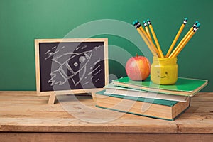 Back to school background with books, pencils in emoji jar, apple, chalkboard and rocket sketch