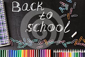 Back to school background with colorful felt tip pens, pencils, clips, notebook and the title Back to school written by