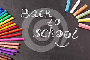 Back to school background with colorful felt tip pens and title Back to school written by white chalk